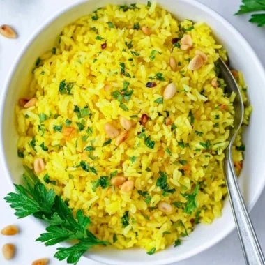 Served bowl of Mediterranean yellow rice garnished with fresh herbs.