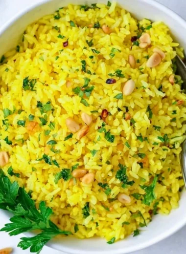 Served bowl of Mediterranean yellow rice garnished with fresh herbs.