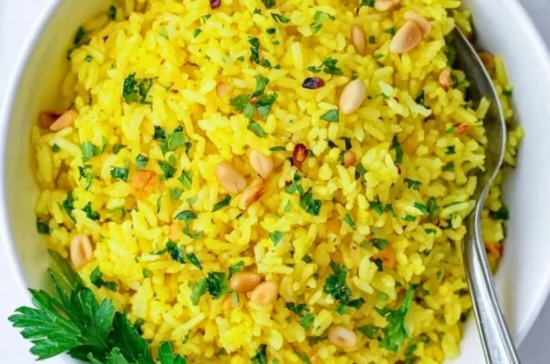 Served bowl of Mediterranean yellow rice garnished with fresh herbs.