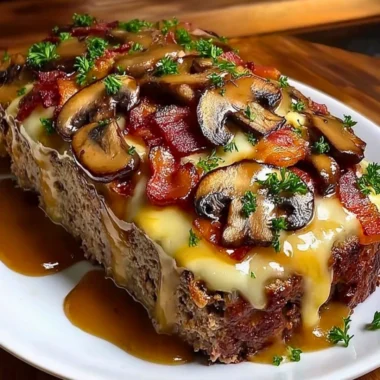 Delicious Swiss Bacon Mushroom Meatloaf topped with cheese and mushrooms