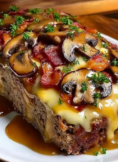 Delicious Swiss Bacon Mushroom Meatloaf topped with cheese and mushrooms