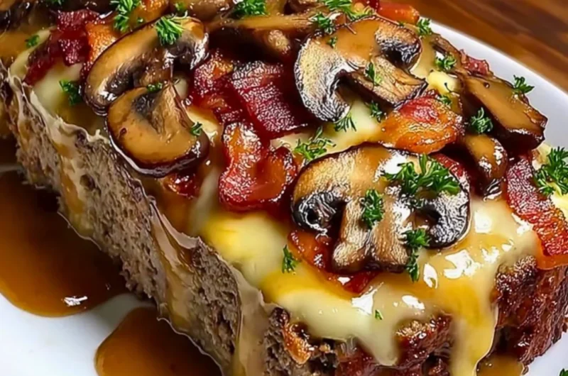 Delicious Swiss Bacon Mushroom Meatloaf topped with cheese and mushrooms
