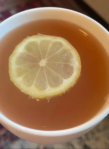 Glass of refreshing Citrus Mint Peach Tea with mint leaves and peach slices