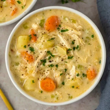 High protein chicken pot pie soup in a bowl garnished with herbs