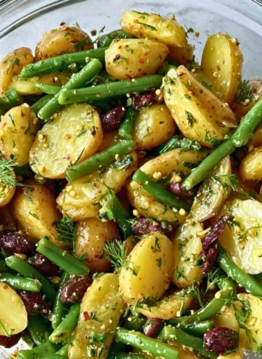 Delicious potato salad with green beans, Kalamata olives, and capers served in a bowl.