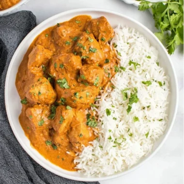 Delicious slow cooker butter chicken served with rice and garnished with cilantro