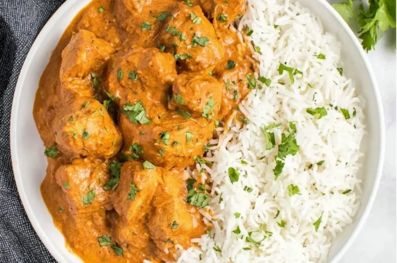 Delicious slow cooker butter chicken served with rice and garnished with cilantro