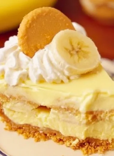 Slice of banana pudding cheesecake topped with whipped cream and banana slices