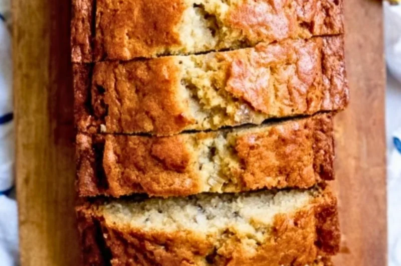 Delicious loaf of banana bread served with sliced bananas and nuts.