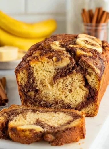 A loaf of cinnamon swirl banana bread with slices cut, showcasing the cinnamon swirl detail.
