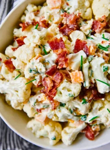 A delicious loaded cauliflower salad topped with fresh vegetables and dressing