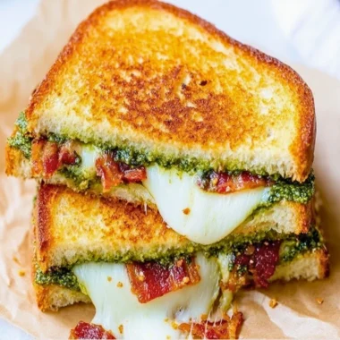 Melted pesto grilled cheese sandwich with fresh basil and golden bread