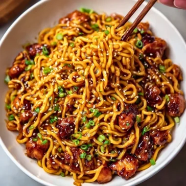 Sticky garlic chicken noodles served in a bowl with fresh vegetables