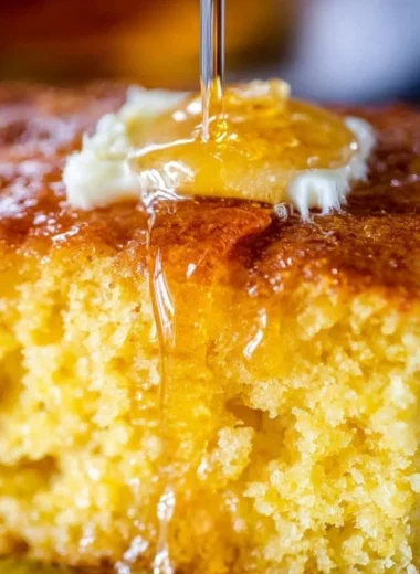 Delicious slice of homemade cornbread, sweet and moist, on a wooden table.