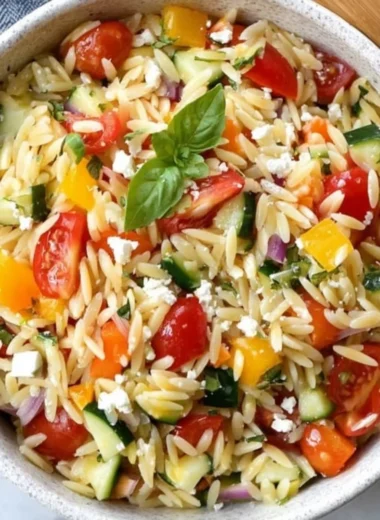 Vegetarian orzo salad with fresh vegetables served in a bowl.