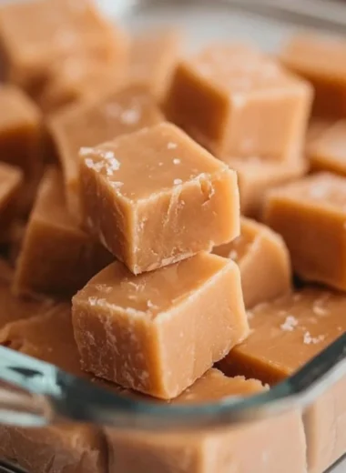 Decadent peanut butter fudge cut into squares on a white plate.