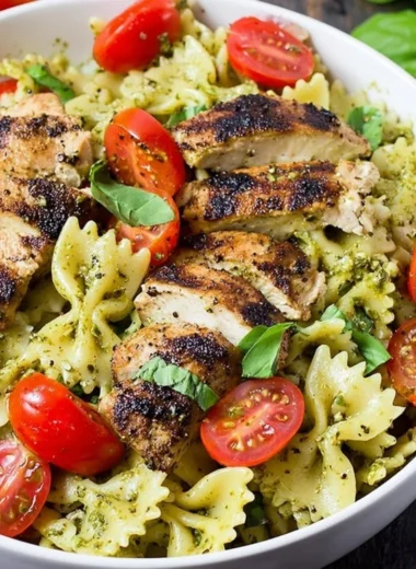 Pesto Pasta with Grilled Chicken served on a plate garnished with fresh basil