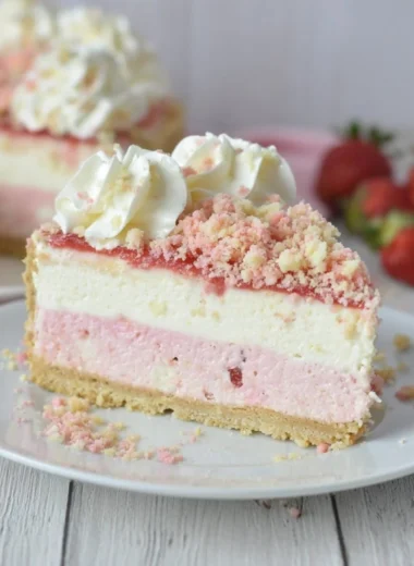 A slice of Strawberry Crunch Cheesecake topped with fresh strawberries and crunch.