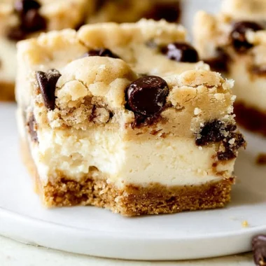 Delicious chocolate chip cheesecake bars with a creamy topping and chocolate chips