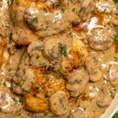 Plate of chicken marsala with pasta and rich sauce garnished with herbs