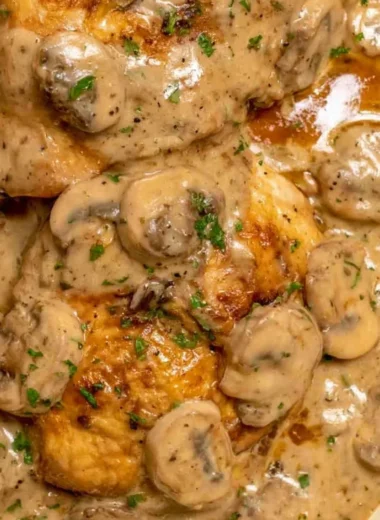 Plate of chicken marsala with pasta and rich sauce garnished with herbs
